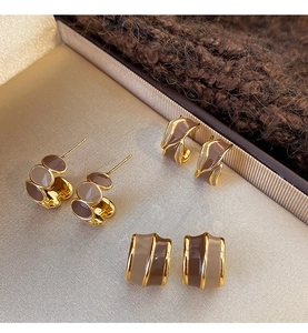 Close-up of three vintage enamel C-shape stud earrings set in a beige velvet jewelry box