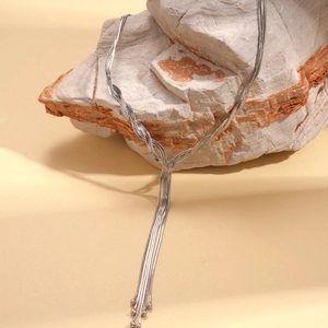 Detail of silver multi-layer snake chain necklace with tassels on textured rock