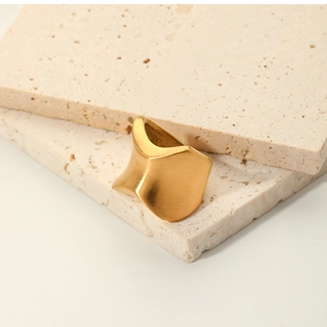Detail of wide irregular matte gold ring placed on natural textured stone slabs