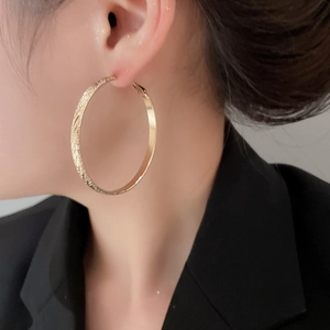 Close-up of gold textured hoop earrings showing scale and elegant style on a model