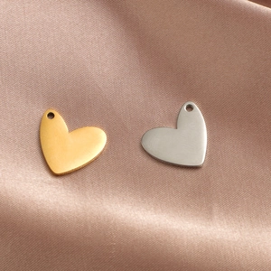 Minimalist heart pendants in gold and silver stainless steel on soft satin fabric