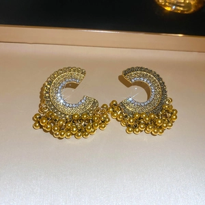 Detail of vintage gold C-shaped earrings with rhinestones and bead tassel fringe