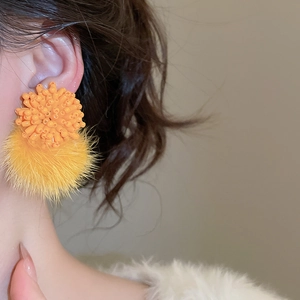 Close-up of elegant orange cluster stud earrings with yellow fluffy pom-poms for women