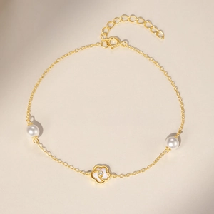 Dettaglio macro del ciondolo a fiore dorato con diamante e perle su catena elegante