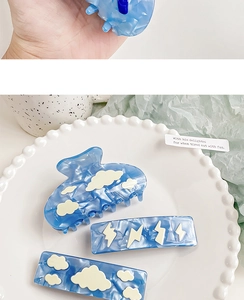 Blue acetate hair clip set with cloud and lightning patterns on a white display plate