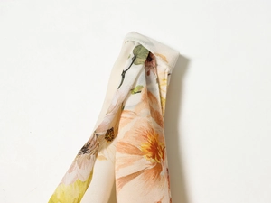 Detailansicht des Sommerblumenmusters auf leichtem orange-beigem Chiffon-Stoff