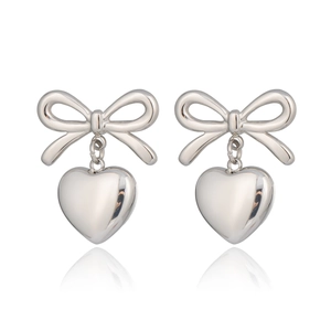 Close-up of silver steel bow earrings with hanging heart charms on a white background