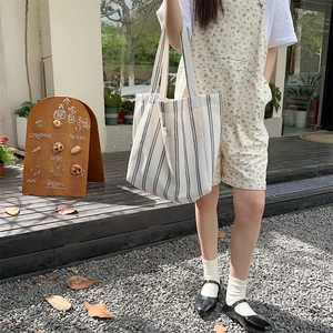 Close-up of a large capacity striped canvas tote bag with woven label and accordion side folds