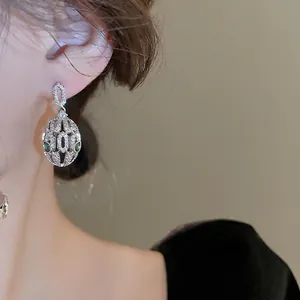 Silver snake-head dangle earrings with sparkling white zircons and green gemstone eyes