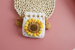Detail of handmade crochet drawstring pouch with sunflower pattern and heart charm