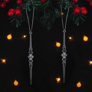 Close-up of clear icicle Christmas tree pendants hanging on pine branches with berries