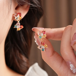 Detail of colorful zircon butterfly drop earrings on model with gold finish