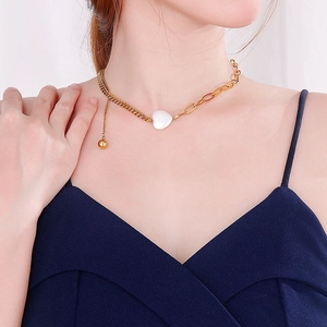 Asymmetric gold necklace with white heart shell pendant and cuban link chain