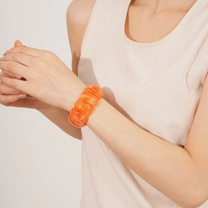 Close-up of bright orange acrylic geometric stretch bracelet with ribbed texture details