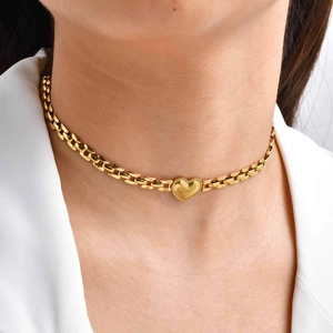 Collana con ciondolo a cuore dorato e catena a maglie rettangolari indossata da una donna in abito