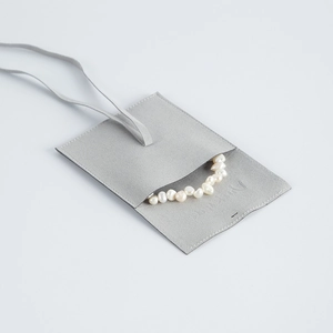 Detail of light grey microfiber jewelry pouch with an irregular pearl necklace inside
