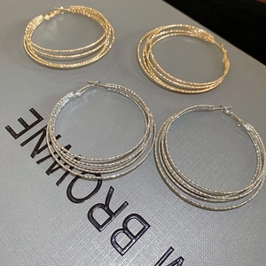 Detail of layered gold and silver hoop earrings with frosted texture on gift box