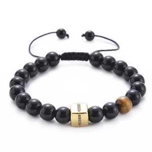 Macro view of black agate beads and brown tiger eye stone with golden cubic zirconia charm