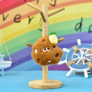 Close-up of cute brown plush chicken leg keychain with pineapple decor on wooden stand