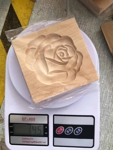 Rectangular beech wood cookie mold with rose carving on a scale weighing 145g
