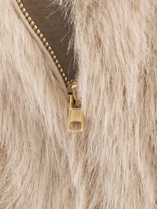 Close-up of golden metal zipper on beige faux fur jacket showing long plush texture
