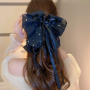 Détail d'une pince à cheveux en mousseline noire à pois argentés et longs rubans en soie