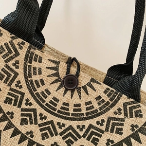 Detail of the black button closure and ethnic pattern on the natural linen tote bag