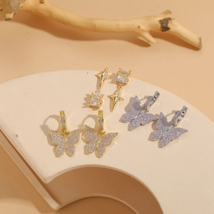 Macro detail of butterfly hoop earrings with pink zircons on a textured stone base