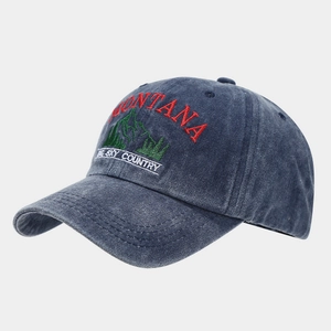 Detail of embroidered Montana mountain logo on washed navy blue cotton baseball cap