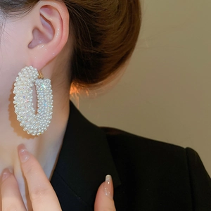 Detail of large gold hoop earring with pavé set white pearls and sparkling rhinestones
