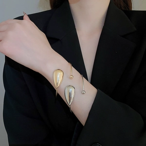 Detailed view of gold and silver teardrop open bracelets worn on the wrist