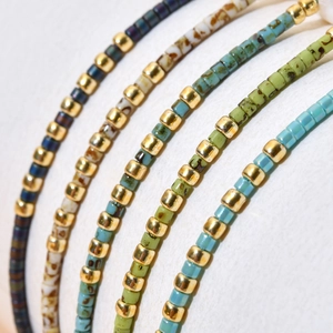 Handmade bohemian beaded bracelets with colorful square beads and gold spacers on white
