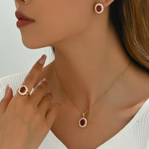Elegant gold jewelry set with oval red zircon necklace, earrings and ring on model