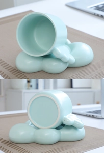 Detail of creative mint green ceramic mug with cloud handle and matching cloud base saucer