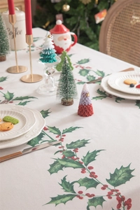 Close-up of Christmas tablecloth with holly leaves and red berries on beige fabric
