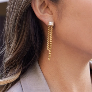 Boucles d'oreilles pendantes dorées avec zircon carré, présentées sur un mannequin