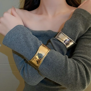 Close-up of model wearing gold and silver wide irregular pleated cuffs with polished finish