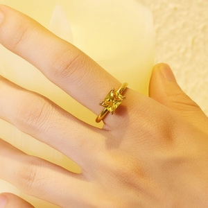Macro shot of a 18K gold plated ring with a square yellow gemstone on a finger
