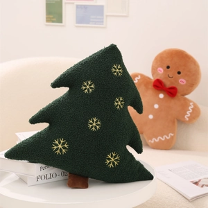 Detail of plush green Christmas tree pillow with golden snowflake embroidery and brown trunk