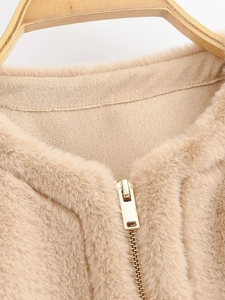 Close-up of the soft beige faux fur texture and smooth gold metal zipper on the vest