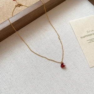 Dettaglio del ciondolo a cuore rosso in cristallo su una catena dorata su tessuto morbido