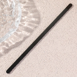 Close-up of minimalist matte black stainless steel open cuff bracelet on stone texture