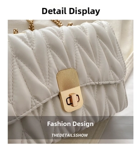 Detail of white pleated shoulder bag with V-shaped texture and gold metal chain strap