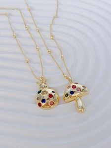 Close-up of gold-plated necklaces with colorful beetle and mushroom crystal pendants