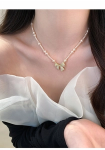 Detail van een Franse retro parelketting met een fonkelende hanger met zirkonia strik