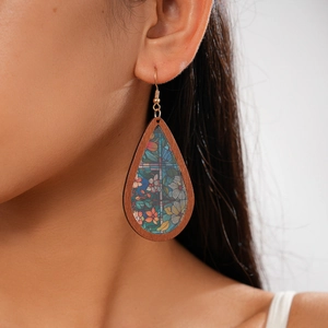 Detail of wooden teardrop earring with vintage stained glass print on a model