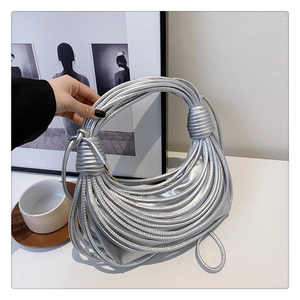 Detail of silver knot-handle handbag featuring multi-strand metallic finish design