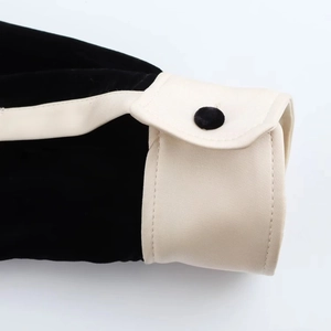Détail de la manche en velours noir avec poignet en satin blanc et bouton assorti