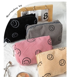 Detailed view of corduroy makeup bags in four colors with embroidered smiley faces