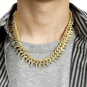 Close-up of golden iced-out thorn Cuban chain necklace worn by a male model